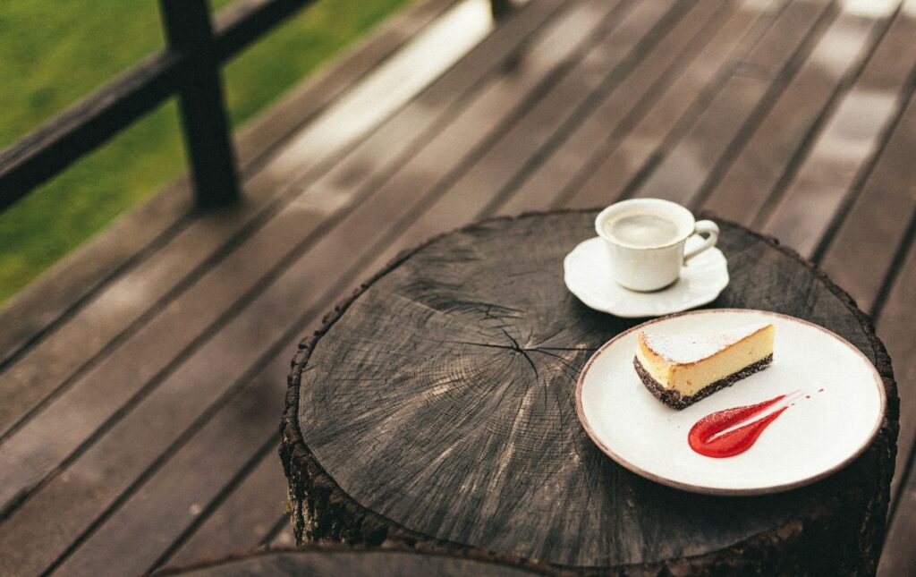 Cheesecake and coffee sit on a rustic table.